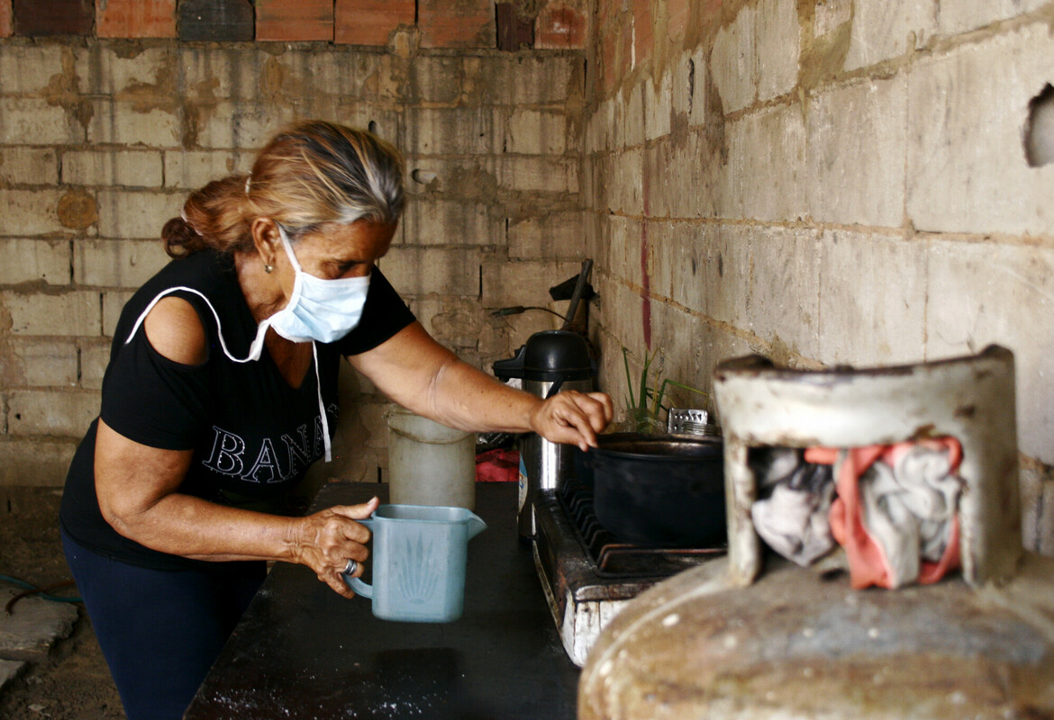 Nuvis from Venezuela står i sitt kök och tappar upp vatten i en karaff.