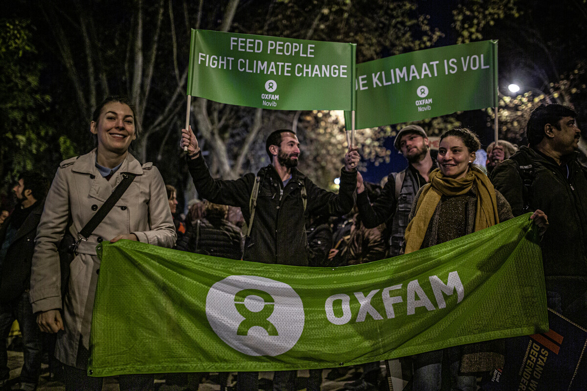 Klimatdemonstration. Två kvinnor ler och håller i en banner där det står "Oxfam".