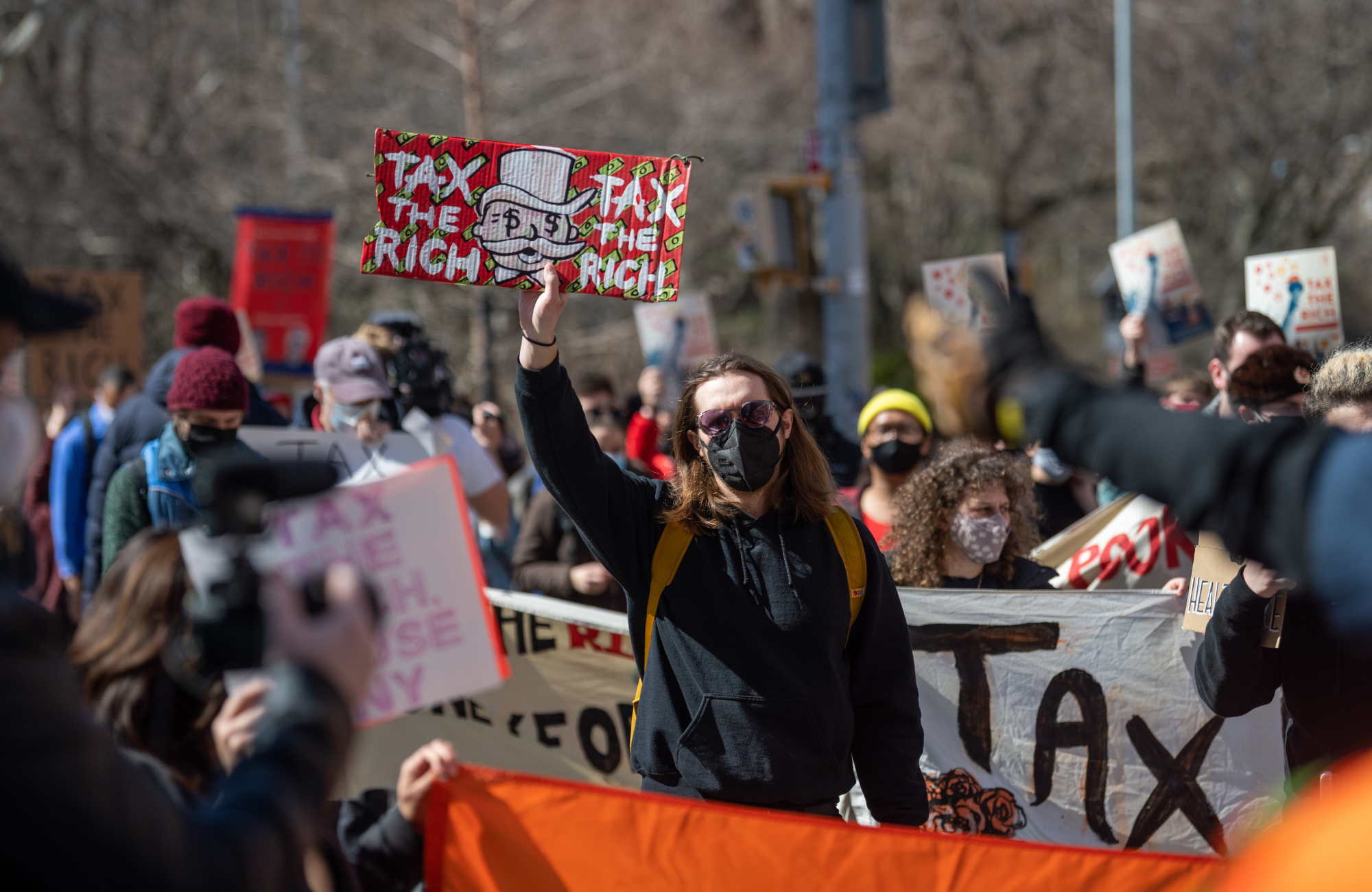 Person i demonstration som håller upp en skylt med texten "Tax the rich"