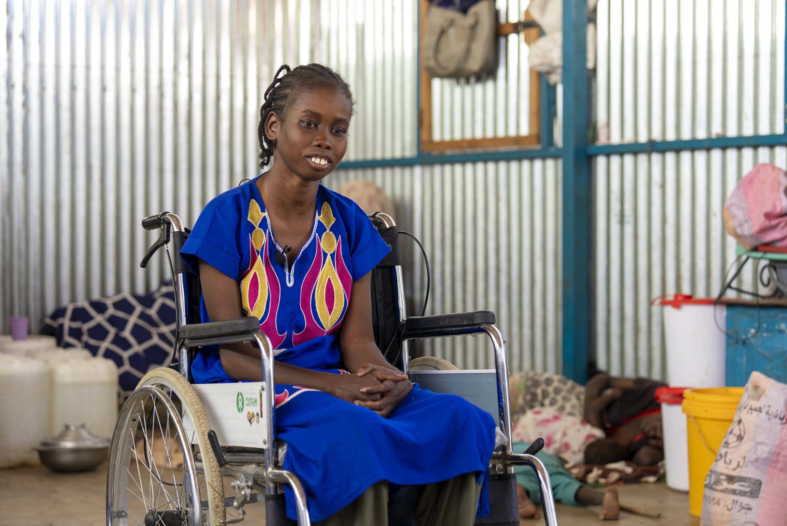 Sunday Dak som flytt från Sudan har på sig en blå klänning och sitter i en rullstol.